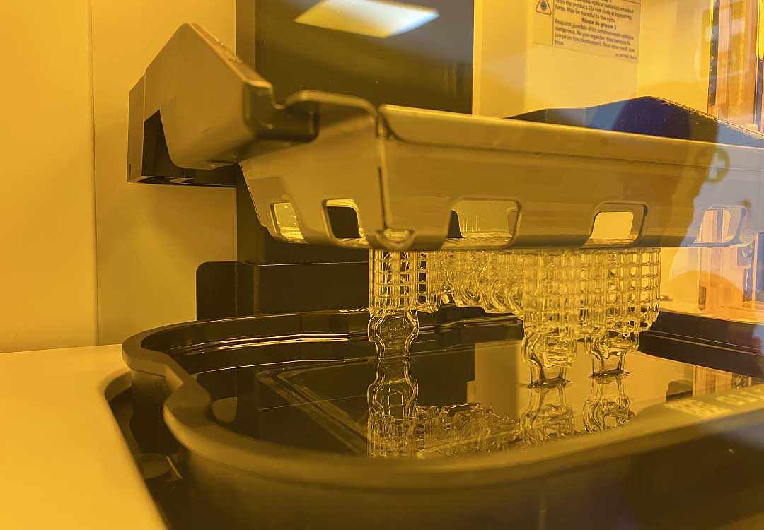 3D printer in action, printing a detailed prototype using resin, illustrating the process of preparing a 3D file for resin printing.